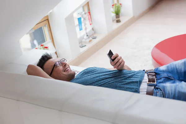 Muž chytrý telefon vleže — Stock fotografie