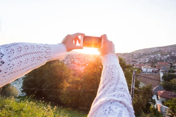 Vrouw neemt foto met smartphone bij zonsondergang — Stockfoto