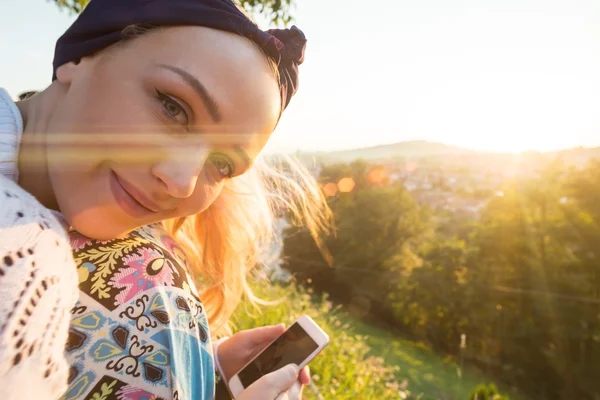 Vrouw neemt foto met smartphone bij zonsondergang — Stockfoto