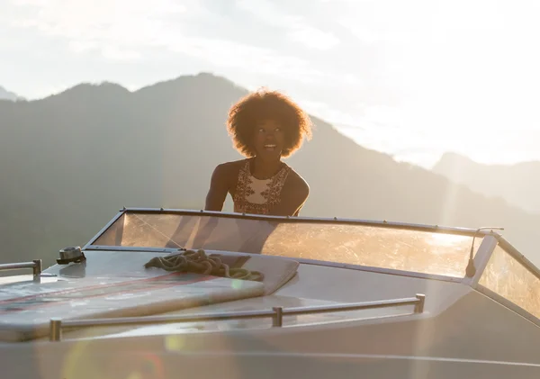 Zomervakantie - afro jongedame besturen van een motorboot op sunse — Stockfoto