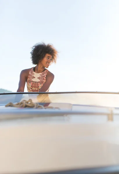 Vacances d'été - jeune femme afro conduisant un bateau à moteur sur le soleil — Photo