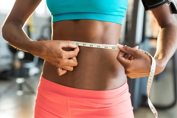 Woman measuring waist in gym — Stock Photo, Image