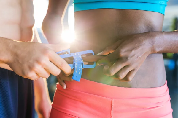 Allenatore misurare il grasso corporeo della donna sportiva — Foto Stock