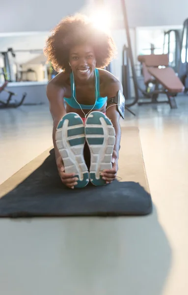 Kvinnan sträcker sig på matta i gymmet — Stockfoto