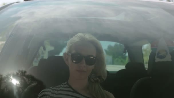 자동차, 자동차와 여자 그녀의 머리 스타일의 유리에 반사에에서 그녀의 머리 롤빵을 만드는 여자 — 비디오