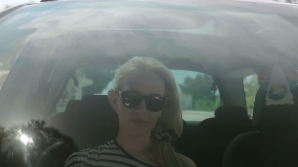 Chica haciendo su moño de pelo en el coche, reflexión sobre el vidrio de un coche y la niña peinando su cabello — Vídeos de Stock