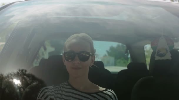 Menina fazendo seu pão de cabelo no carro, reflexão sobre o vidro de um carro e menina styling seu cabelo — Vídeo de Stock