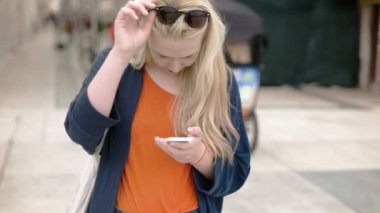Sarışın turist telefon ang güneş gözlüğü koyarak üzerine yazarak