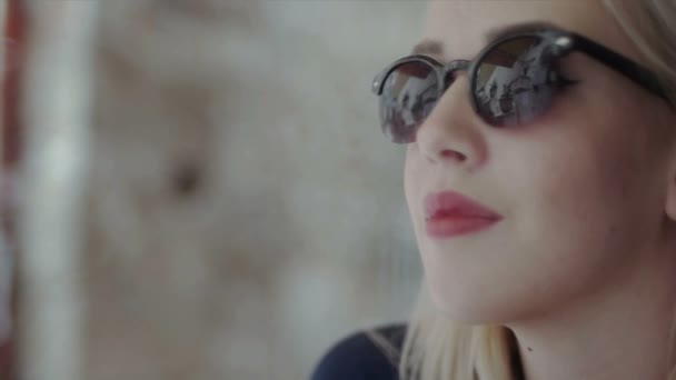 Blondes Mädchen mit Sonnenbrille lächelt in die Kamera — Stockvideo