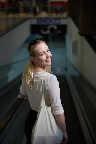 Blonde fille dans le shopping descendre les escaliers et sourire — Photo