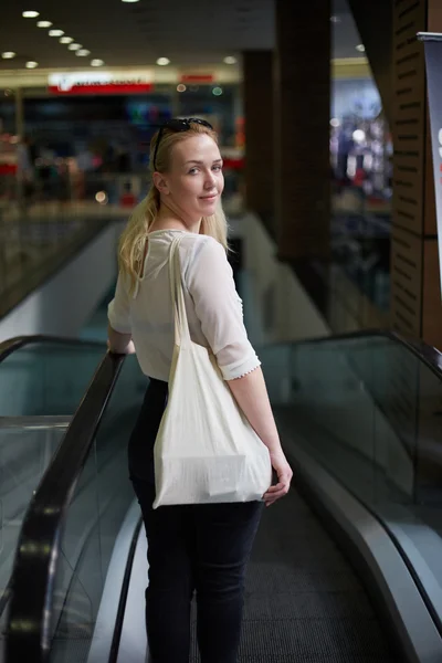 Blonde fille dans le shopping descendre les escaliers et sourire — Photo