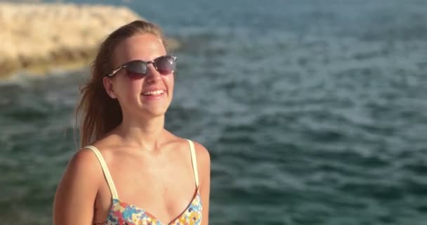 Hübsche Frau, die auf der Klippe steht und die Wellen genießt — Stockvideo