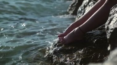 Cliff üzerinde duran ve su ile kız güneşin tadını deniz yanında sıçrayan kız