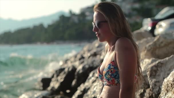 Mädchen steht auf der Klippe und planscht mit Wasser, Mädchen am Meer genießt die Sonne — Stockvideo