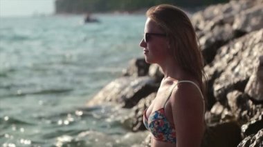 Cliff üzerinde duran ve su ile kız güneşin tadını deniz yanında sıçrayan kız