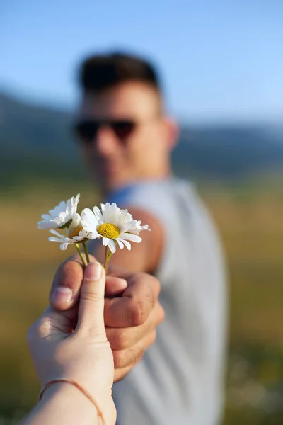 Мальчик дарит цветы девушке за камерой — стоковое фото