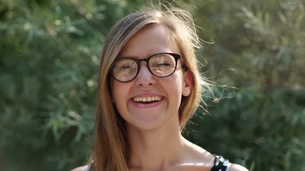 Ragazza con gli occhiali sorridente alla macchina fotografica, ragazza nerd godendo il sole e sorridente bella ragazza sorridente nella natura — Foto Stock