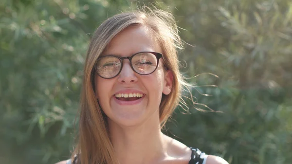 Chica con gafas sonriendo a la cámara, chica nerd disfrutando del sol y sonriendo hermosa niña sonriendo en la naturaleza —  Fotos de Stock