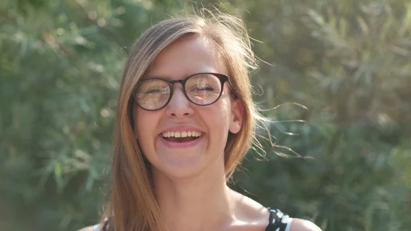 Fille avec des lunettes souriant à la caméra, fille nerd profiter du soleil et souriant belle jeune fille souriant dans la nature — Photo