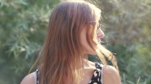 Chica con gafas sonriendo a la cámara, chica nerd disfrutando del sol y sonriendo hermosa niña sonriendo en la naturaleza — Vídeos de Stock