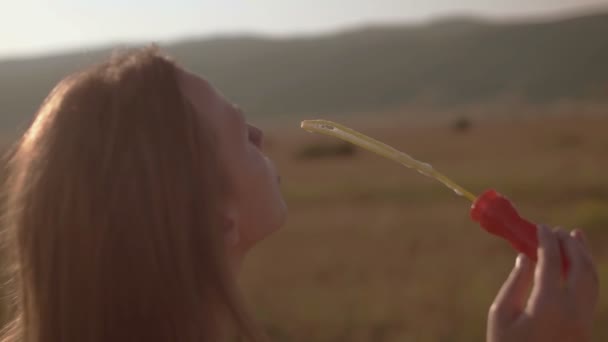 Menina soprando bolhas na natureza, colorido — Vídeo de Stock