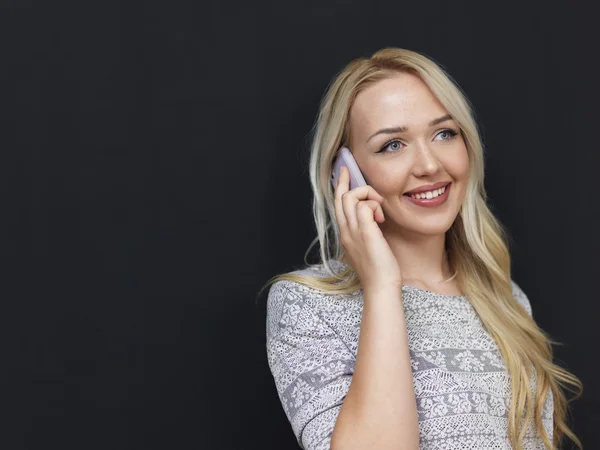 Mujer bastante rubia en el fondo de pizarra usando el teléfono celular — Foto de Stock