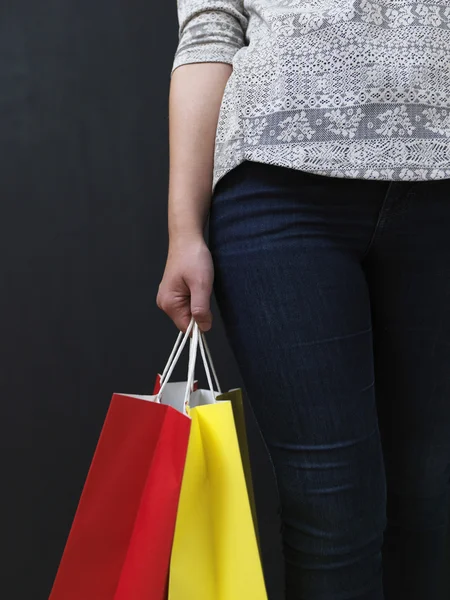 Alışveriş torbaları üzerinde bir kara tahta arka plan ile sarışın kız — Stok fotoğraf