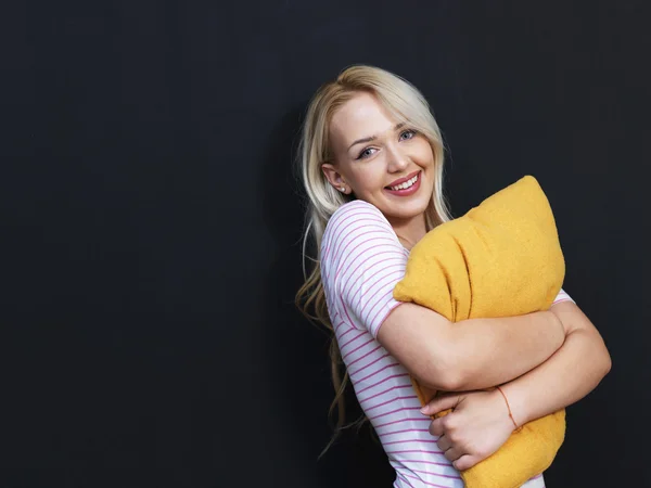 Vrouw met kussen in studio, op zwarte achtergrond — Stockfoto