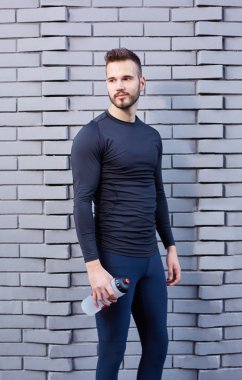 Enerji içecek w t-shirt holding şişe erkek koşucu gülümseyen