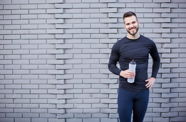 Sonriente corredor masculino en camiseta sosteniendo botella de bebida energética w — Foto de Stock