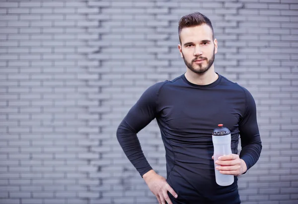 Sorrindo corredor masculino em t-shirt segurando garrafa de bebida energética — Fotografia de Stock