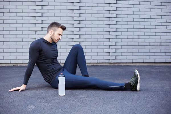 Hombre deportivo con barba estirándose contra muro de hormigón — Foto de Stock