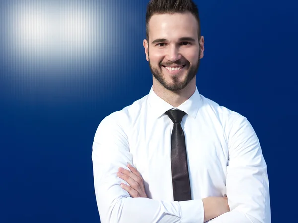 Empresario frente a fondo azul sonriendo — Foto de Stock