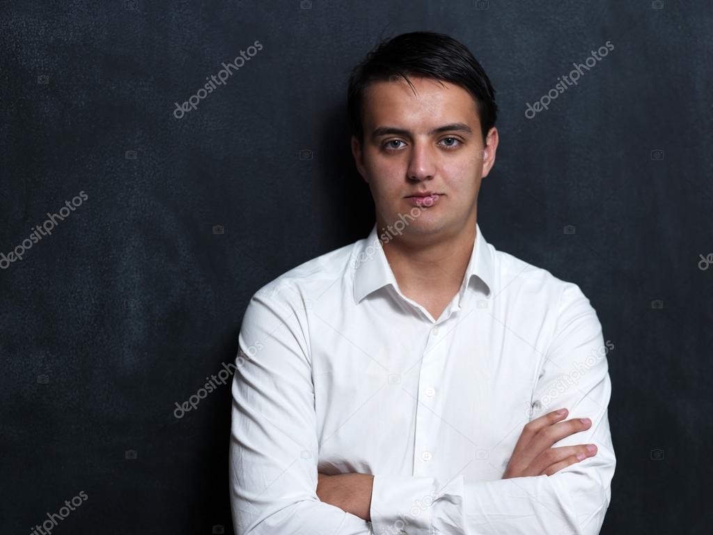 Portrait of a serious young man standing against chalkboard