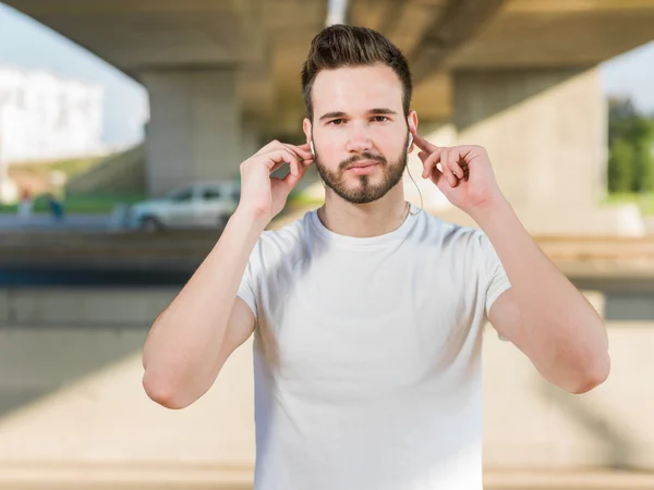 Jeune homme beau courant le long de la rue et de l'autoroute sous le pont — Photo