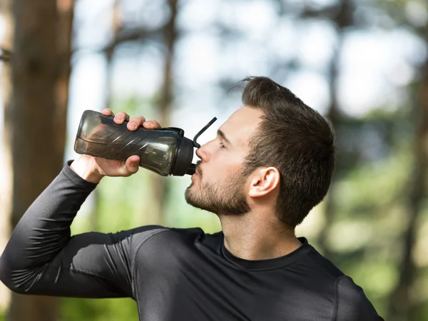 Knappe man drinkwater op een zonnige dag — Stockfoto