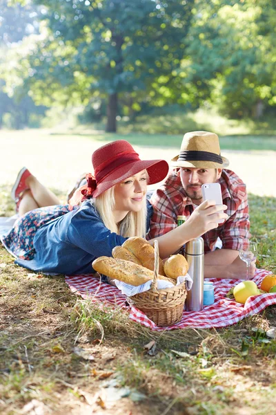 Composiet van paar nemen selfie op smartphone op romantische picknick — Stockfoto