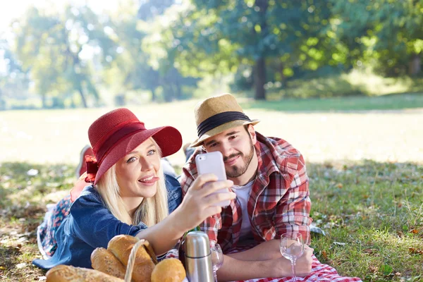 Composiet van paar nemen selfie op smartphone op romantische picknick — Stockfoto