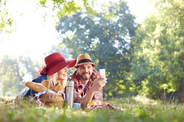 Composiet van paar nemen selfie op smartphone op romantische picknick — Stockfoto