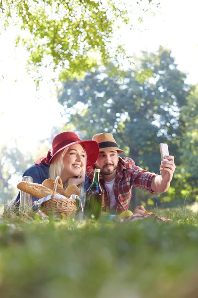 Composiet van paar nemen selfie op smartphone op romantische picknick — Stockfoto