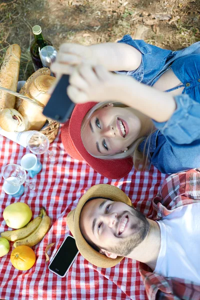 Composiet van paar nemen selfie op smartphone op romantische picknick — Stockfoto