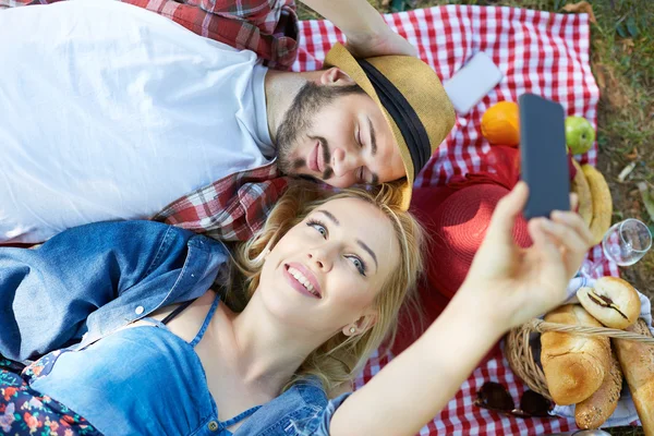 Composiet van paar nemen selfie op smartphone op romantische picknick — Stockfoto