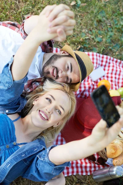 Composiet van paar nemen selfie op smartphone op romantische picknick — Stockfoto