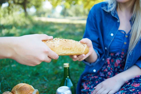 Woman and man tearing a bread outside on a picnic — Stock Photo, Image