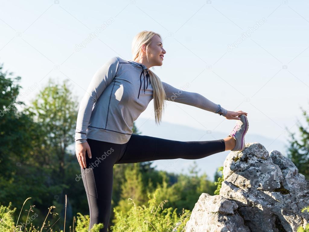 Young woman stretching before running in the early evening