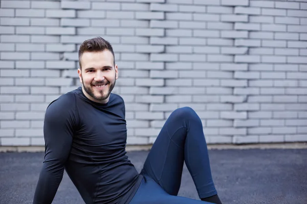 Hombre deportivo con barba estirándose contra muro de hormigón — Foto de Stock