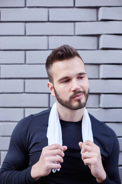 Jonge gespierde man met een witte handdoek hebben een rust na het joggen — Stockfoto