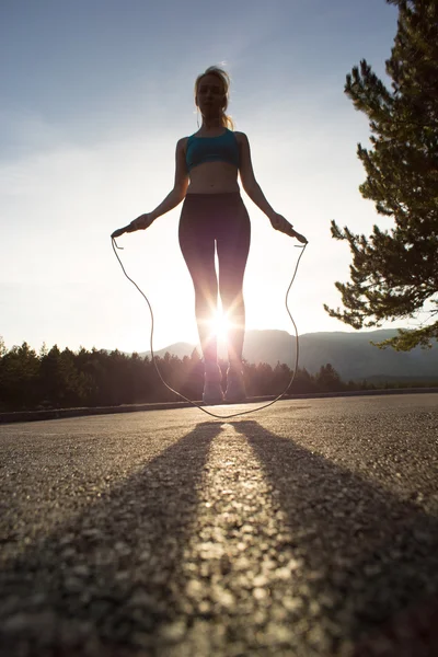 Active young woman jumping with skipping rope outdoors — Stock Photo, Image