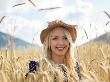 Genç kadın saman tarlasında doğanın ve güneş ışığının tadını çıkarıyor.