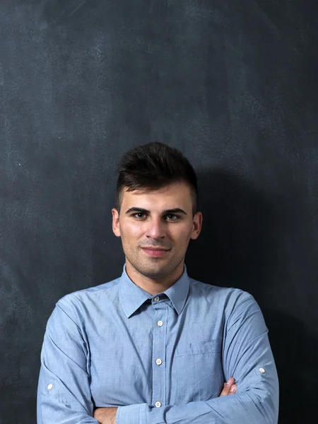 Portrait of a serious young man standing against chalkboard — Stock Photo, Image